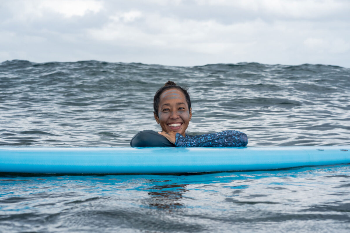 girl smiling laying on surfboard