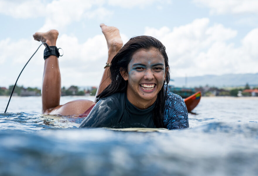 girl smiling while laying on surfboard
